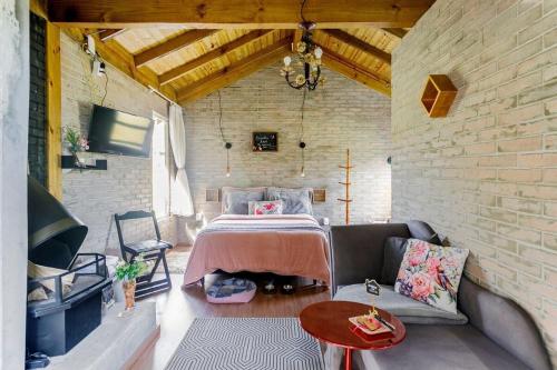 um quarto com uma cama e um sofá numa parede de tijolos em O Chalé Encantado - Rancho Queimado em Rancho Queimado