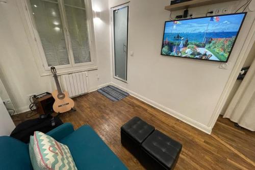 ein Wohnzimmer mit einem blauen Sofa und einer Gitarre in der Unterkunft Lovely love nest near Paris in Clichy