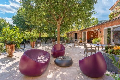 a patio with purple chairs and tables and a tree at Logis Hôtel Restaurant Le Pradinas in Anduze