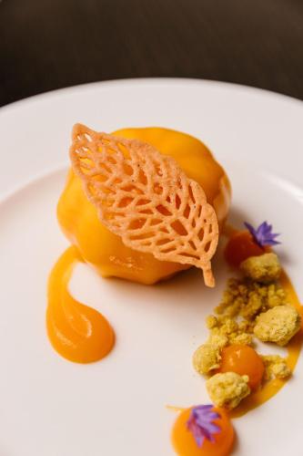 a white plate with a piece of fruit and sauce at The Guardsman - Preferred Hotels and Resorts in London