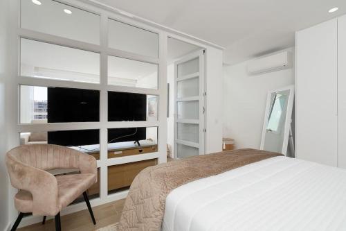 ein Schlafzimmer mit einem Bett, einem Stuhl und einem Fenster in der Unterkunft Stylish Beachfront Escape . Steps to Beach . Wifi in Portimão