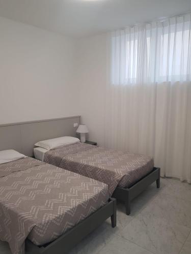 two beds sitting in a room with a window at HOTEL LORENA in Toscolano Maderno