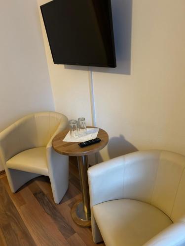 a room with two chairs and a table with a tv at Gasthof Wildschönauer Bahnhof in Wörgl