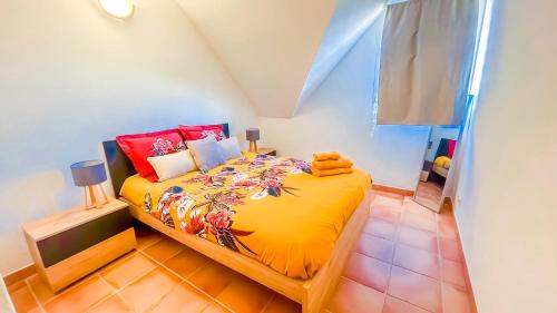 um quarto com uma cama amarela e almofadas vermelhas em Magnifique Appartement Fleurs Caraïbes - 6 personnes en résidence avec piscine privée - Sainte Anne em Sainte-Anne