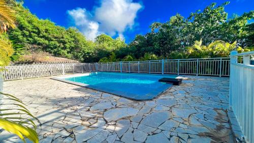 uma piscina num quintal com uma cerca em Magnifique Appartement Fleurs Caraïbes - 6 personnes en résidence avec piscine privée - Sainte Anne em Sainte-Anne