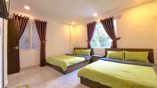 een slaapkamer met twee bedden en een raam bij Uyên House hotel in Da Lat