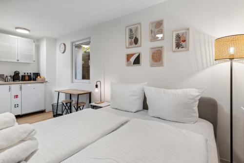 Vorstadtoase - Apartment für 2 Personen mit Smart TV, Parken, eigenen Bad, Netflix - Nähe BER في Eichwalde: غرفة نوم بيضاء مع سرير ومطبخ