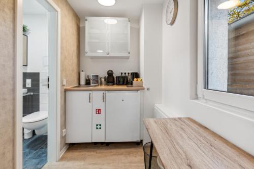 una pequeña cocina con armarios blancos y una mesa en Vorstadtoase - Apartment für 2 Personen mit Smart TV, Parken, eigenen Bad, Netflix - Nähe BER en Eichwalde