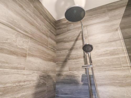 a shower in a bathroom with a stone wall at Calidum Cor in Doncaster