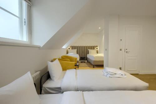 a white room with two beds and a yellow chair at Nunne Boutique Hotel in Tallinn