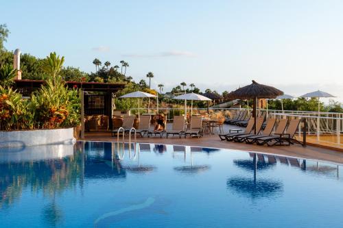 - une piscine avec des chaises longues et des parasols dans un complexe dans l'établissement Wyndham Residences Costa Adeje, à Adeje