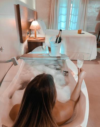 a woman in a bath tub with a glass of wine at Hiu Hotel in Juquei