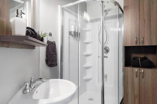 a bathroom with a shower and a white sink at Chouette A - Mont-Tremblant in Mont-Tremblant