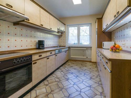 a large kitchen with wooden cabinets and a window at Ferienwohnung Haus Nahetal in Gonnesweiler