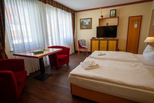 a hotel room with two beds and a table and a television at Hotel Esplanade & Aparthotel Rialto in Binz