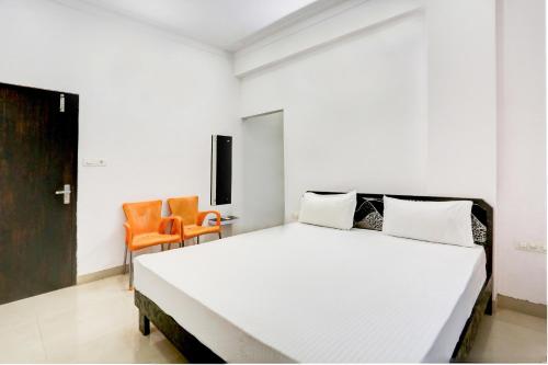 um quarto com uma grande cama branca e cadeiras laranja em Super OYO Hotel Goverdhan Villa em Udaipur