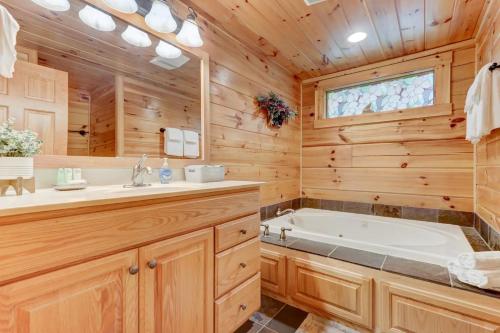 Cabaña de madera con baño con bañera y lavamanos en LUX 4BD Lodge w/ Views! Fire Pits + HOT TUB + Pool, en Gatlinburg