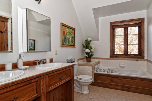 a bathroom with two sinks and a toilet and a tub at Manoir B - Mont-Tremblant in Mont-Tremblant