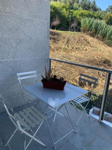 a white table and a chair and a potted plant at Acogedor apartamento en Baiona in Baiona