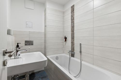 a white bathroom with a tub and a sink at Vorstadtoase - 3 Personen - Apartment mit Queensize-Bett, Badewanne, Schlafcouch, Parken, Netflix, Nähe BER in Eichwalde