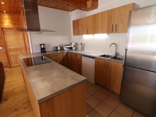 une cuisine avec des armoires en bois et un réfrigérateur en acier inoxydable dans l'établissement Appartement Moderne, 14 Pers, Proche Pistes, Sauna, WIFI, Animaux Acceptés - FR-1-502-360, à Tignes