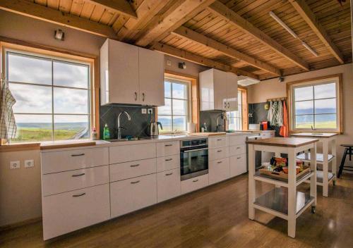 uma cozinha com armários brancos, uma mesa e janelas em Fagrafell Hostel em Skogar