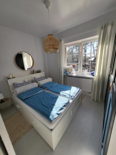 sypialnia z łóżkiem z niebieskimi prześcieradłami i oknem w obiekcie APARTAMENT przy jeziorze w Bornem-Sulinowie