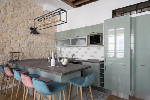 une cuisine avec une grande île dotée de chaises bleues et roses dans l'établissement Typical Parisian Flat#3Bedrooms#Opera#Louvre, à Paris