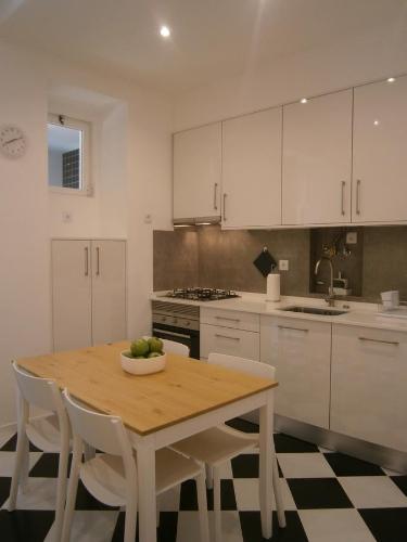 cocina con mesa de madera y armarios blancos en The Estrela Apartment, en Lisboa