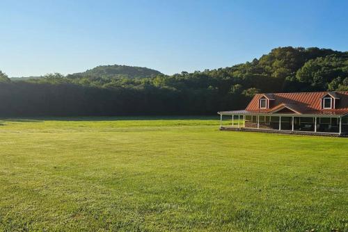 a large grassy field with a house in the foreground at GameRoom, HotTub, Piano, 5mi to OldManCave - Hocking Hills Copper House in Laurelville