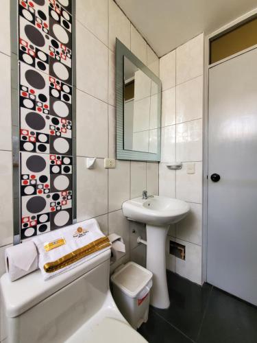 a bathroom with a sink and a toilet and a mirror at Hotel Real San Pedro in El Puente