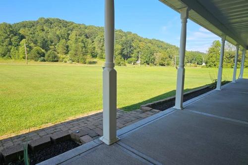 an empty porch with a field of grass and trees at GameRoom, HotTub, Piano, 5mi to OldManCave - Hocking Hills Copper House in Laurelville