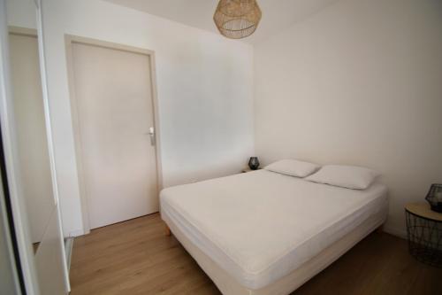 een witte slaapkamer met een bed en een raam bij Appartement cosy à 50 m de la plage et du port in Mèze