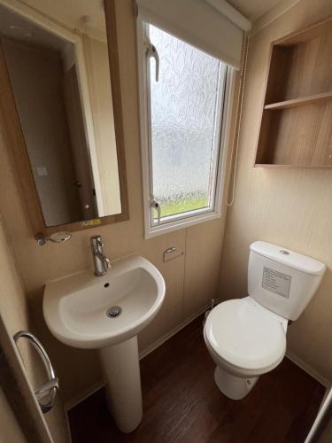 a bathroom with a toilet and a sink and a window at Bittern 13, Scratby - California Cliffs, Parkdean, sleeps 6, pet friendly, bed linen and towels included - close to the beach in Great Yarmouth