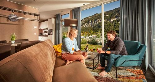 a man and woman sitting on a couch in a living room at Feriendorf Seeblick Toni in Kramsach