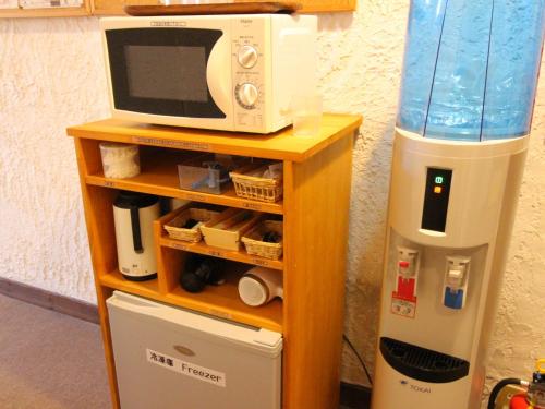 un four micro-ondes sur une étagère à côté d'un réfrigérateur dans l'établissement Hakuba Goryu Pension Kurumi, à Hakuba