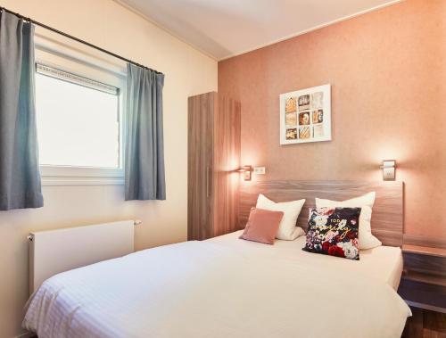 um quarto com uma cama branca com almofadas e uma janela em Feriendorf Seeblick Toni em Kramsach