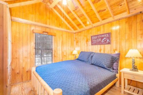 a bedroom with a blue bed in a wooden room at The Weminuche Cabin #80 at Blue Spruce RV Park & Cabins in Tuckerville