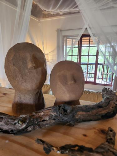 two statues sitting on top of a table with a branch at Amare Cabin in the bush with all your needs! in Marloth Park