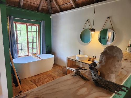 a bathroom with a tub and a sink and a bath tub at Amare Cabin in the bush with all your needs! in Marloth Park