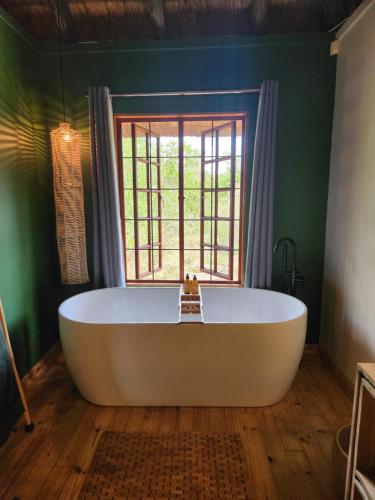 a large bath tub in a room with a window at Amare Cabin in the bush with all your needs! in Marloth Park