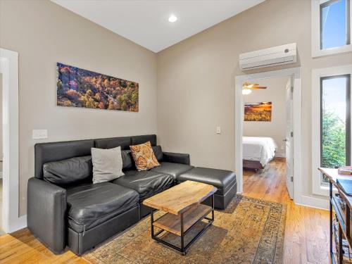 a living room with a black leather couch and a table at Pilot Cove in Pisgah Forest