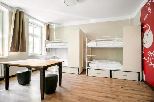 a room with a table and bunk beds at EastSeven Berlin Hostel in Berlin