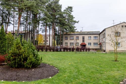 een tuin met bomen en een gebouw op de achtergrond bij Apartamenti Katrīna in Brocēni