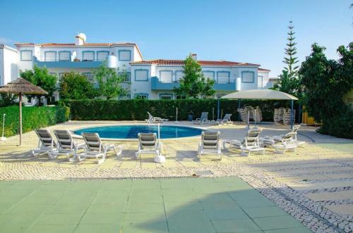 a group of lawn chairs and a swimming pool at Four Bedroom Villa with private pool Oasis Parque AT09 in Portimão