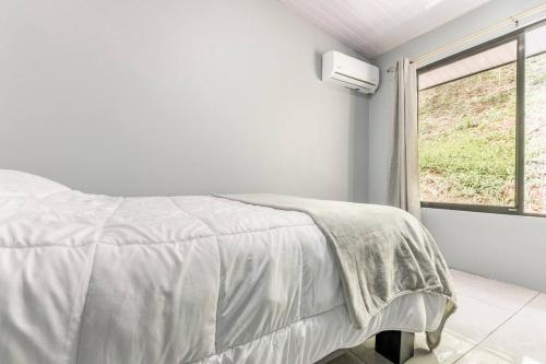 a white bedroom with a bed and a window at Villas Anna Bertha in San Isidro de El General