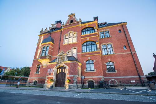a large red brick building on a street at Craft Beer Central Hotel in Gdańsk
