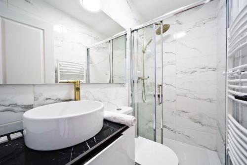 ein weißes Bad mit einem Waschbecken und einer Dusche in der Unterkunft Le Gustave Eiffel - Porte d'Orléans in Gentilly