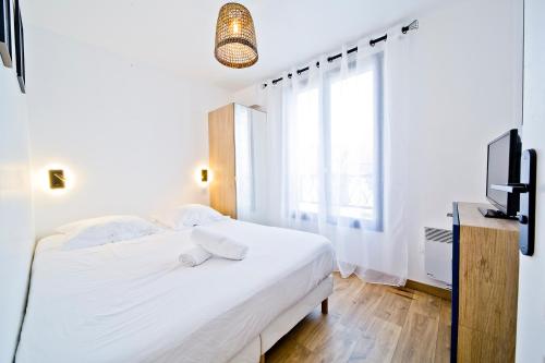 ein weißes Schlafzimmer mit einem Bett und einem TV in der Unterkunft Le Gustave Eiffel - Porte d'Orléans in Gentilly