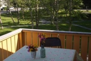 ein Tisch mit einer Flasche und Blumen auf einem Balkon in der Unterkunft Lofoten Center in Kabelvåg